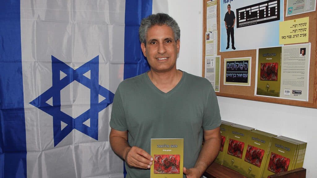 המשורר יהורם גלילי עם הספר פוטו מלחמה, צילום יאיר בן-חיים
