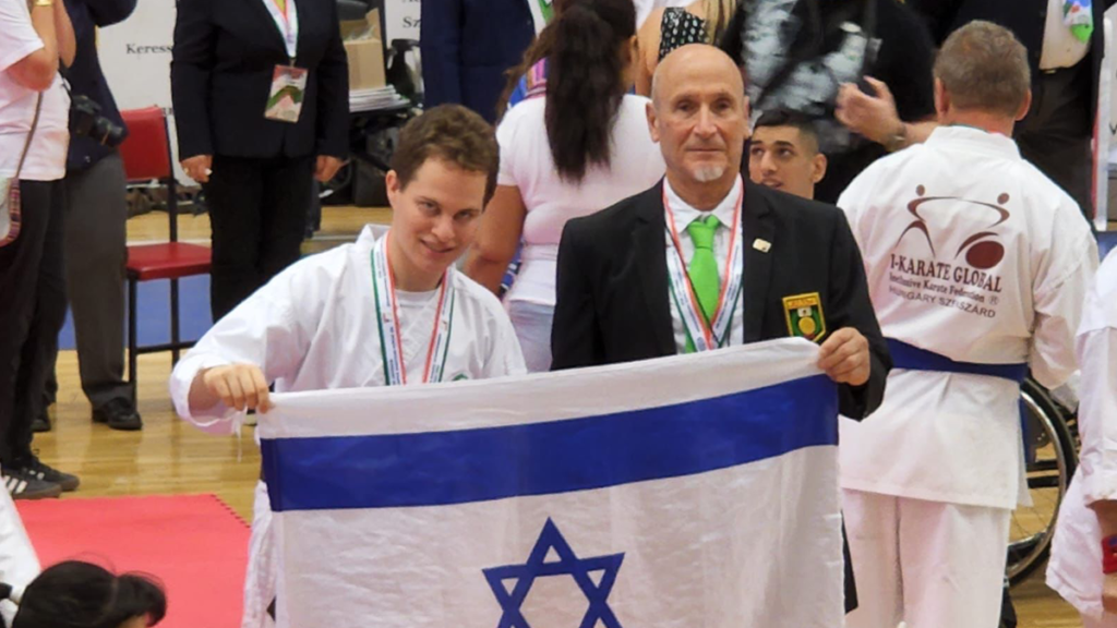 עידן לוי (משמאל) עם מאמנו יוסי שפירא, מניפים את דגל ישראל. צילום באדיבות המשפחה